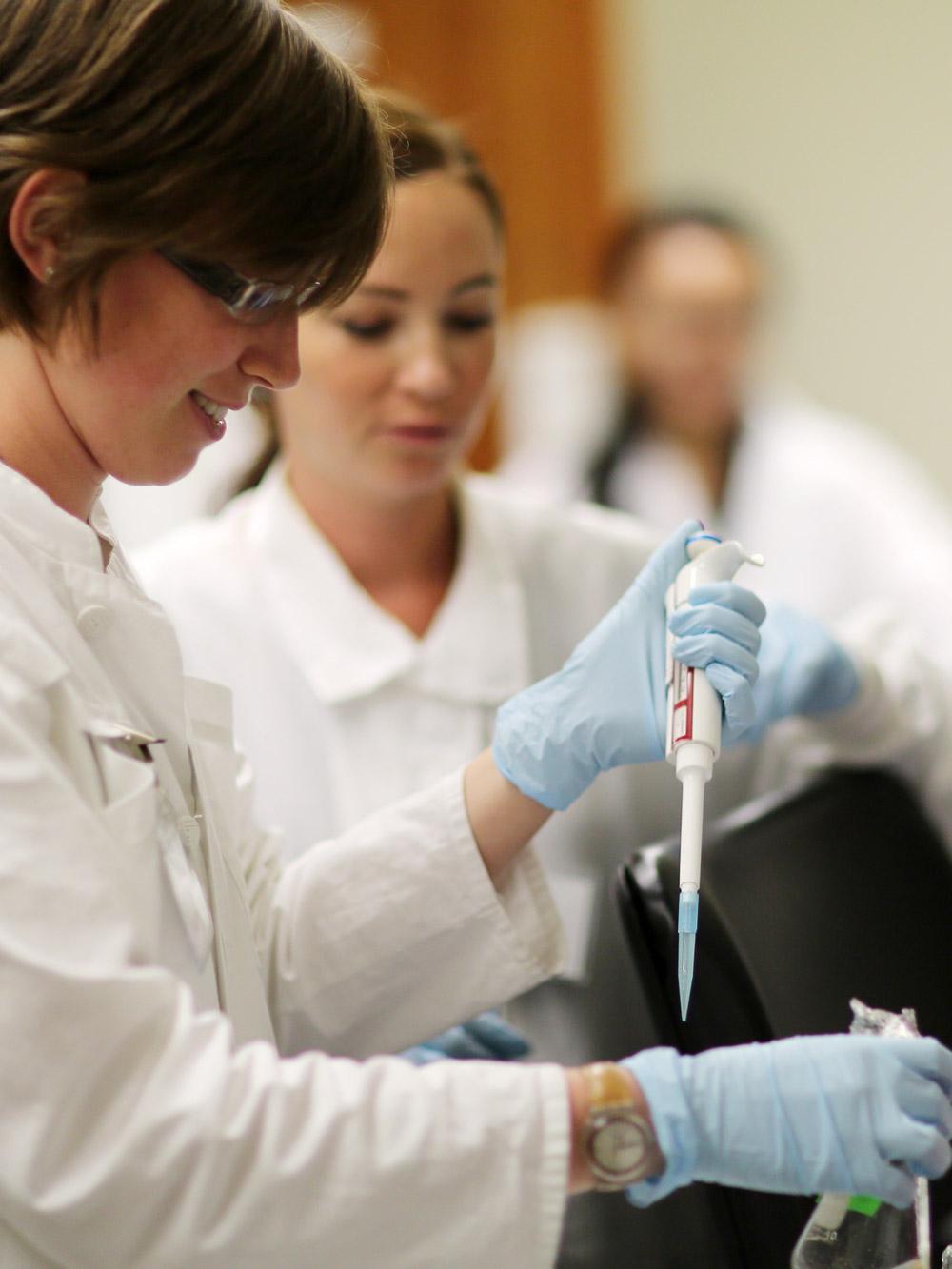 A student using a pipet in a laboratory.